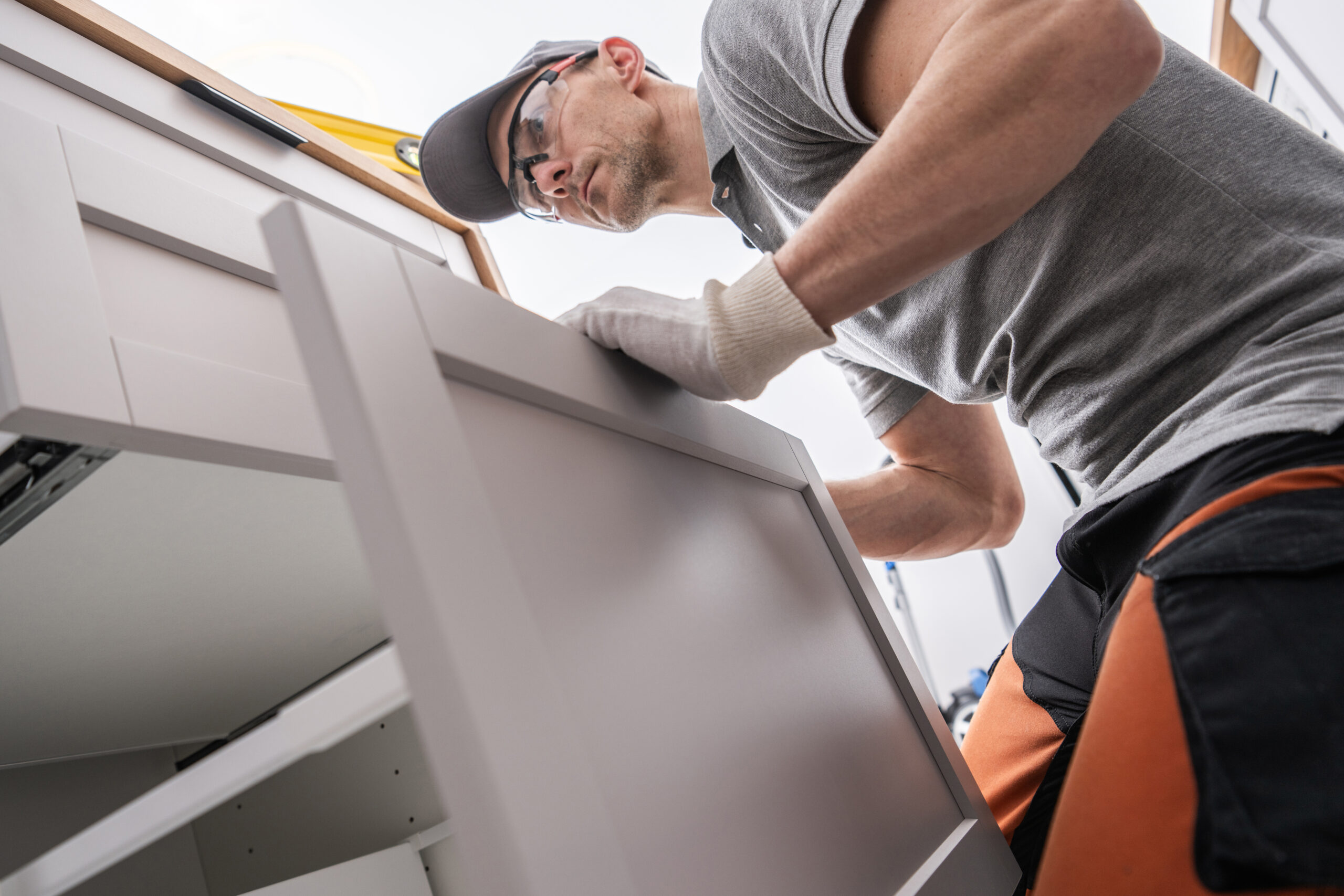 Caucasian professional cCabinetmaker is fixing a kitchen cabinet.